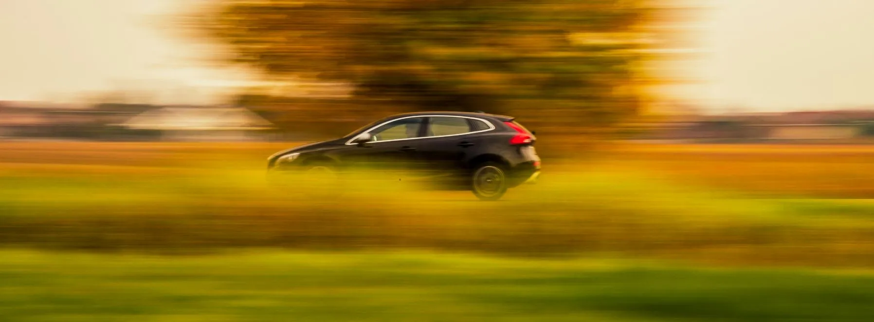 Car driving fast through the countryside on a sunny day, symbolizing freedom and flexibility with a low doc car loan.