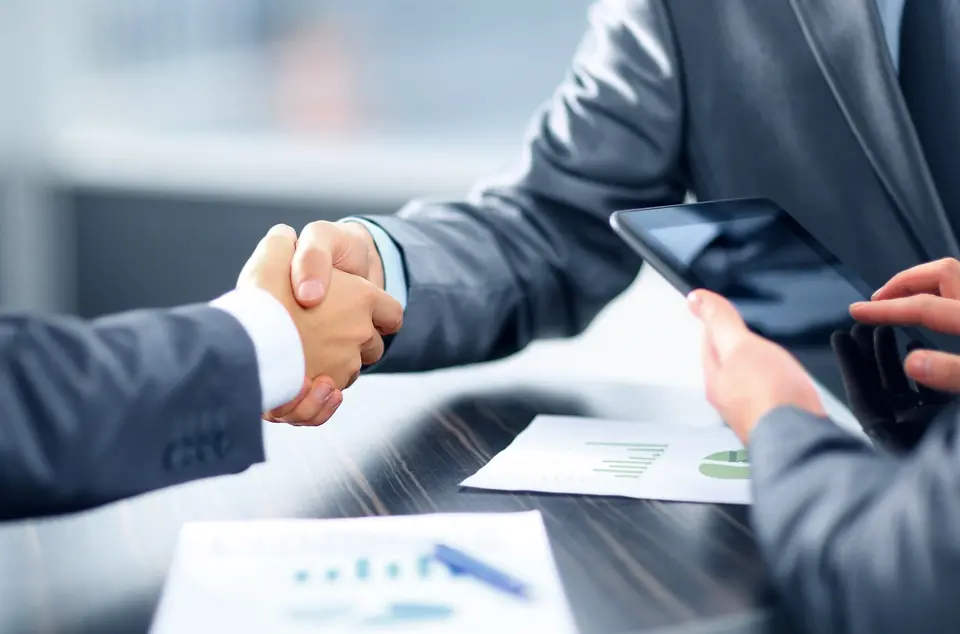 A business car finance broker shaking hands with a business owner, symbolizing a successful car finance partnership.