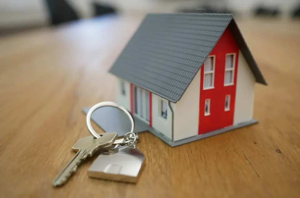 Model house with a set of car keys, representing the choice between mortgage redraw or secured car loan for financing a car.