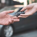Person handing over car keys to buyer showing top tips for buying a car