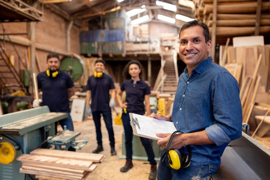 Small business owner working in a wood factory workshop with machinery and timber equipment who may qualify for both the instant asset write-off and equipment finance.